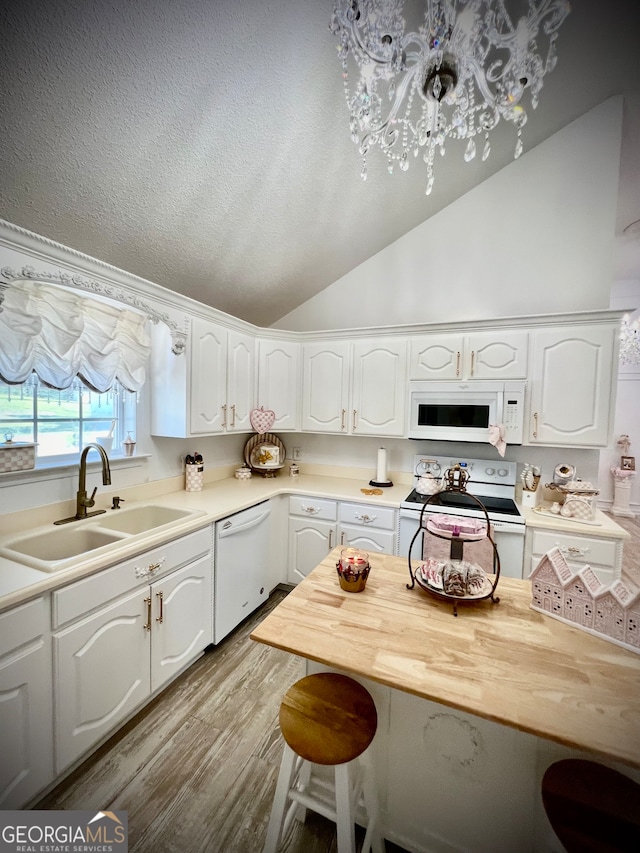 kitchen with light wood-type flooring, white appliances, vaulted ceiling, sink, and white cabinetry