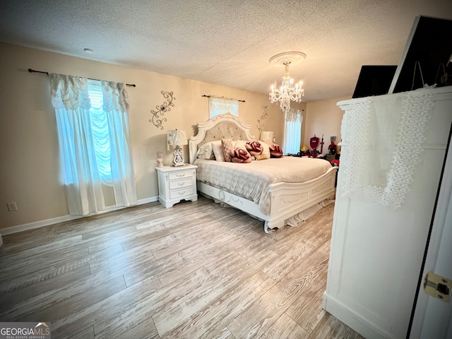 bedroom with an inviting chandelier, a textured ceiling, and light wood-type flooring