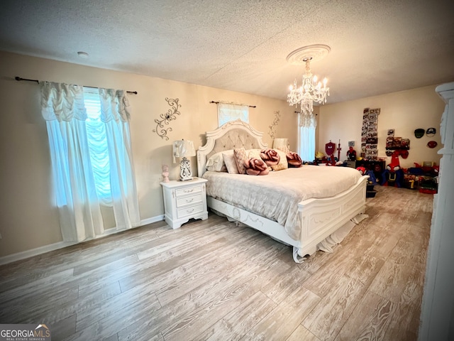 bedroom featuring a textured ceiling, light hardwood / wood-style flooring, and a notable chandelier