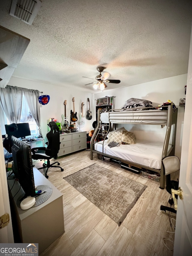 bedroom featuring ceiling fan, light wood-type flooring, and a textured ceiling