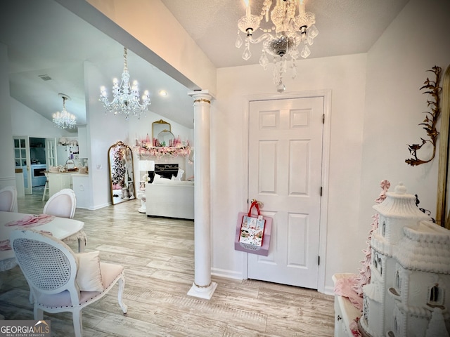 foyer with hardwood / wood-style flooring, an inviting chandelier, and decorative columns