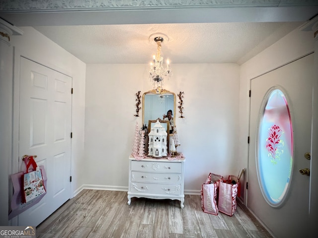 entryway with a chandelier, a textured ceiling, and light wood-type flooring