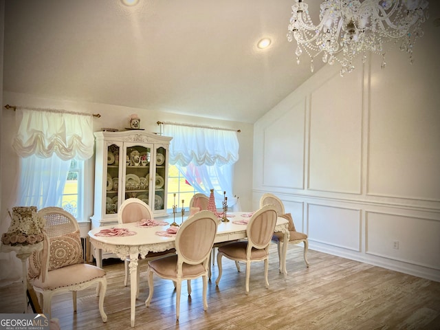 dining space with hardwood / wood-style floors, vaulted ceiling, and a notable chandelier