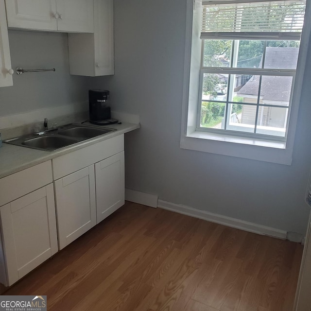 kitchen with light hardwood / wood-style flooring, white cabinets, and sink