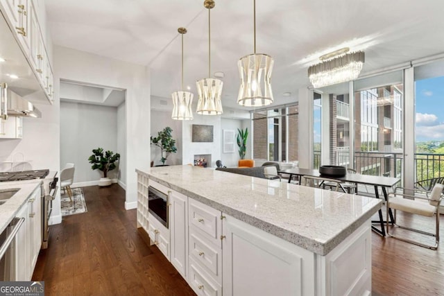 kitchen featuring light stone countertops, appliances with stainless steel finishes, pendant lighting, dark hardwood / wood-style floors, and white cabinetry