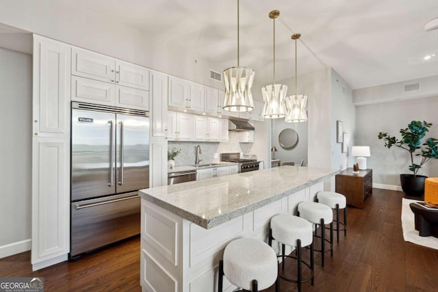 kitchen featuring white cabinetry, dark wood-type flooring, stainless steel appliances, light stone counters, and pendant lighting