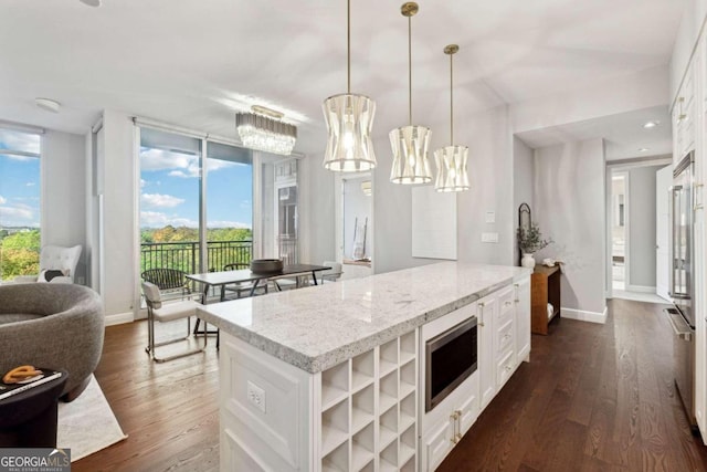 kitchen with pendant lighting, stainless steel microwave, dark wood-type flooring, a kitchen island, and white cabinetry