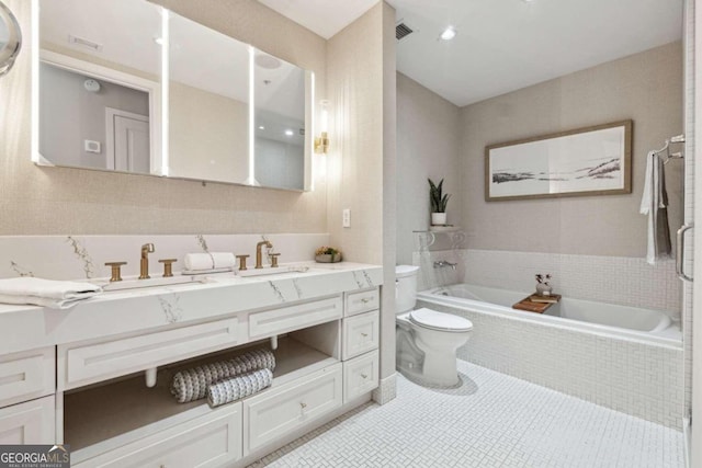 bathroom with tile patterned floors, vanity, a relaxing tiled tub, and toilet