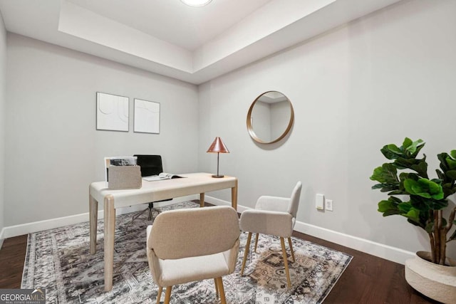 office with a tray ceiling and dark wood-type flooring