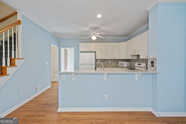 kitchen featuring kitchen peninsula, white cabinetry, light hardwood / wood-style floors, and white appliances