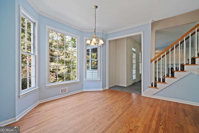 unfurnished dining area featuring plenty of natural light, light hardwood / wood-style floors, and an inviting chandelier