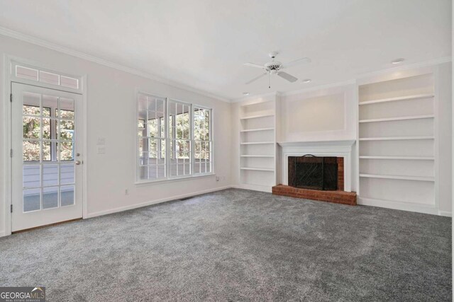 unfurnished living room featuring plenty of natural light, a fireplace, crown molding, and built in shelves