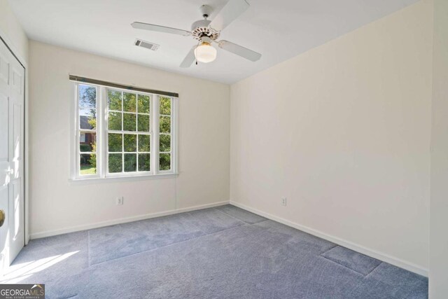 carpeted spare room with ceiling fan