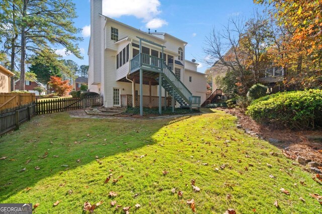 rear view of property featuring a sunroom and a lawn