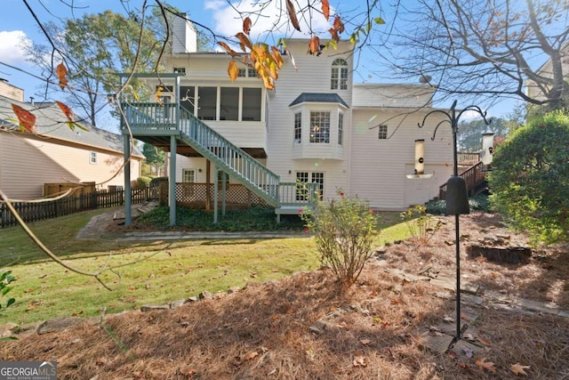 rear view of property featuring a lawn and a sunroom