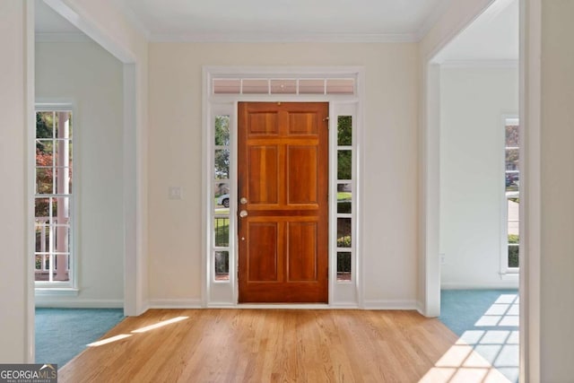 foyer entrance with ornamental molding and light wood-type flooring