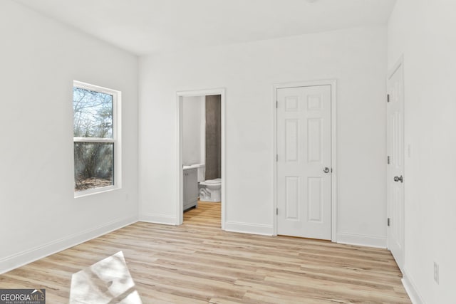 unfurnished bedroom with light hardwood / wood-style floors and connected bathroom