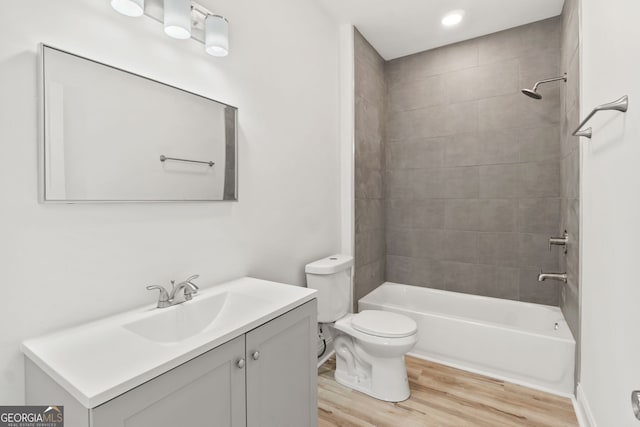 full bathroom featuring toilet, vanity, wood-type flooring, and tiled shower / bath combo