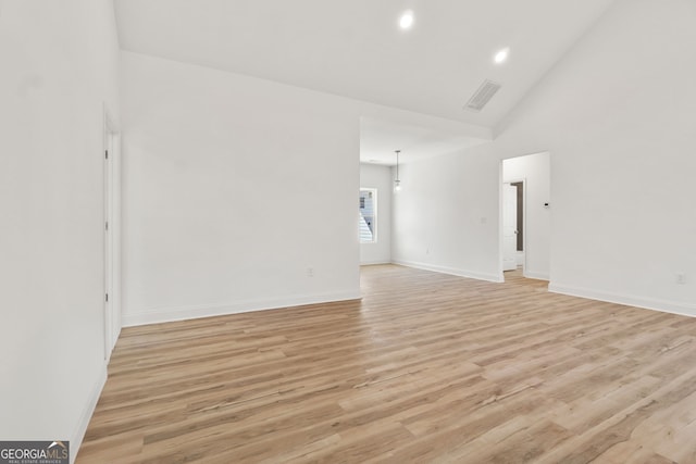 empty room featuring light wood-type flooring and high vaulted ceiling