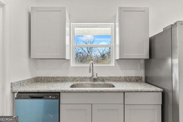 kitchen featuring stainless steel dishwasher, light stone counters, and sink