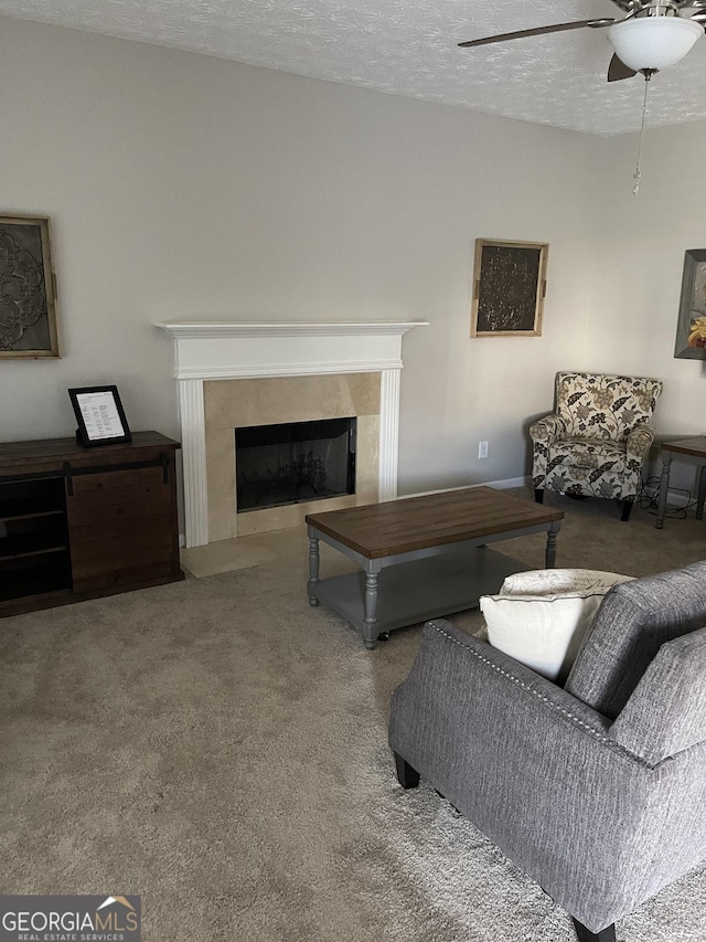 living room featuring ceiling fan, carpet floors, a textured ceiling, and a premium fireplace