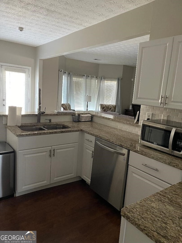 kitchen featuring white cabinetry, dark wood-type flooring, kitchen peninsula, a textured ceiling, and appliances with stainless steel finishes