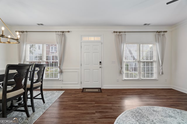 entryway featuring dark hardwood / wood-style flooring, crown molding, and an inviting chandelier