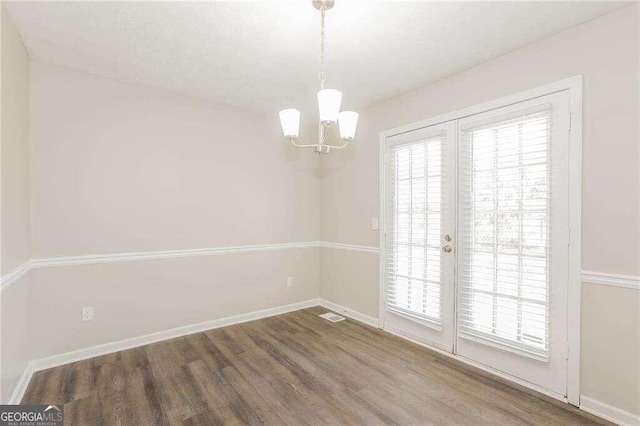 empty room featuring a chandelier and hardwood / wood-style floors