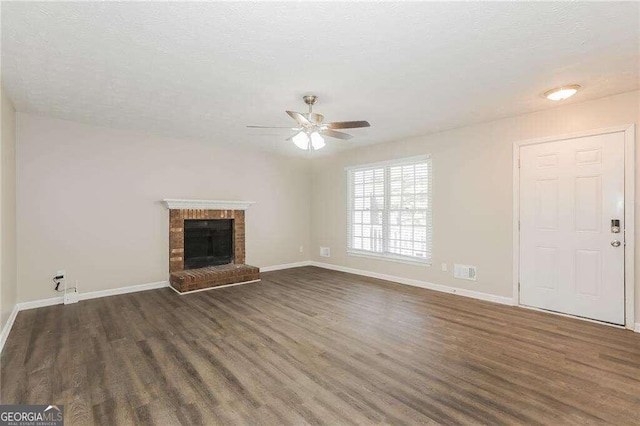 unfurnished living room with a fireplace, ceiling fan, dark hardwood / wood-style flooring, and a textured ceiling