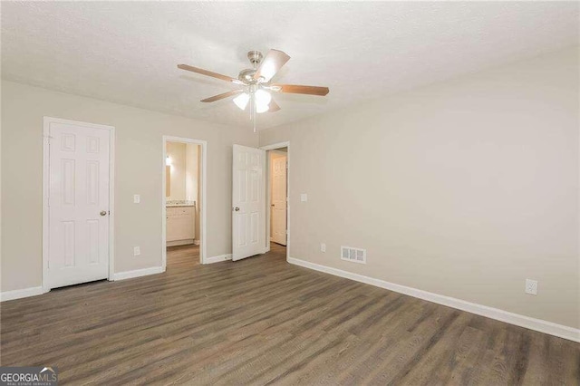 unfurnished bedroom featuring dark hardwood / wood-style floors, ceiling fan, and ensuite bath