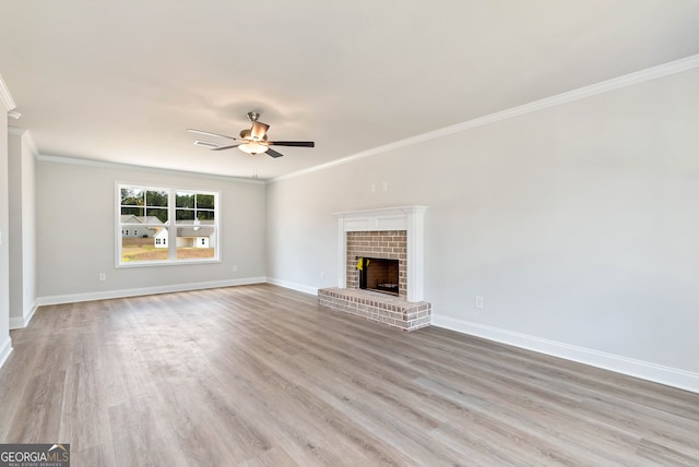 unfurnished living room with ceiling fan, light hardwood / wood-style floors, ornamental molding, and a fireplace