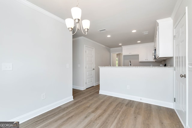 kitchen featuring crown molding, white cabinets, a notable chandelier, and light wood-type flooring