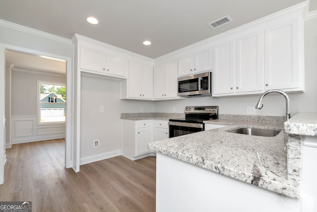 kitchen with light stone countertops, sink, stainless steel appliances, crown molding, and white cabinets