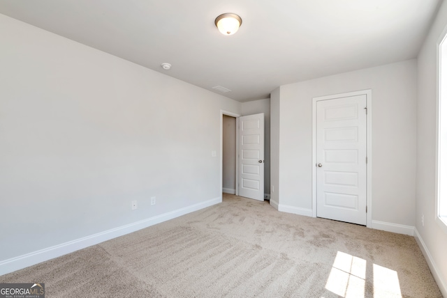 unfurnished bedroom featuring light colored carpet and a closet