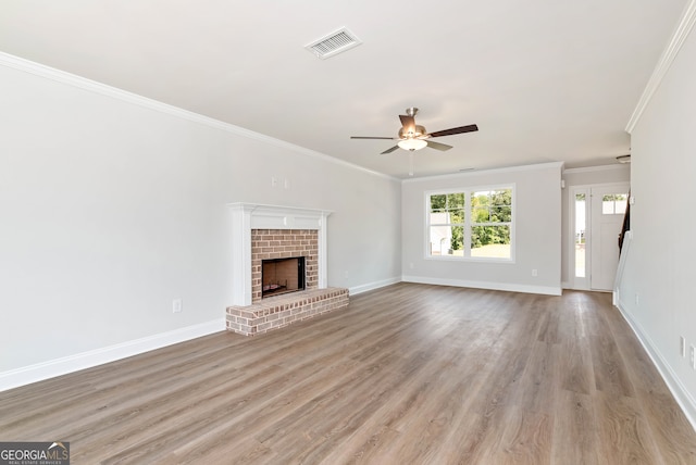 unfurnished living room featuring a fireplace, ceiling fan, crown molding, and light hardwood / wood-style floors