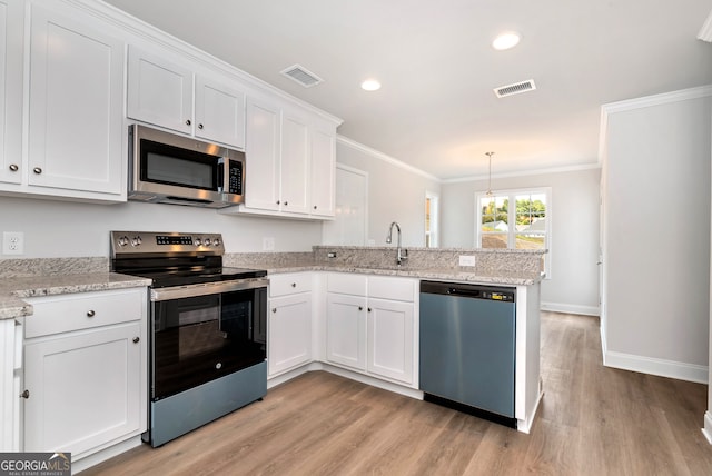 kitchen with kitchen peninsula, appliances with stainless steel finishes, ornamental molding, light hardwood / wood-style floors, and white cabinetry