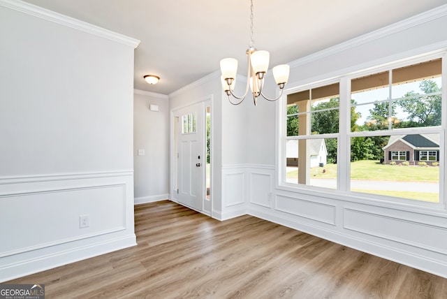 unfurnished dining area featuring a chandelier, hardwood / wood-style floors, and crown molding