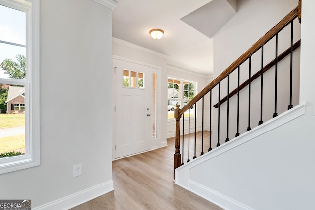 foyer entrance with crown molding and light hardwood / wood-style flooring