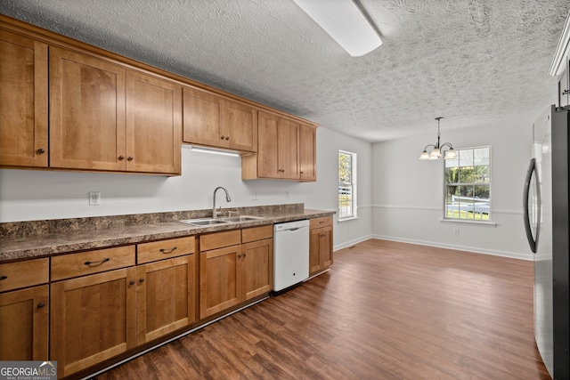 kitchen with stainless steel refrigerator, dishwasher, sink, dark hardwood / wood-style floors, and decorative light fixtures