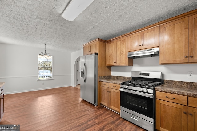 kitchen with a textured ceiling, stainless steel appliances, hanging light fixtures, and dark wood-type flooring