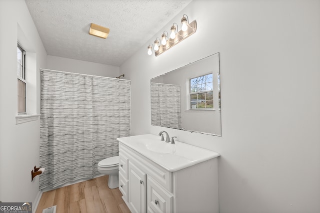 bathroom with vanity, a textured ceiling, hardwood / wood-style flooring, toilet, and curtained shower