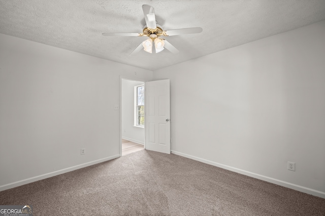 empty room with ceiling fan, carpet floors, and a textured ceiling