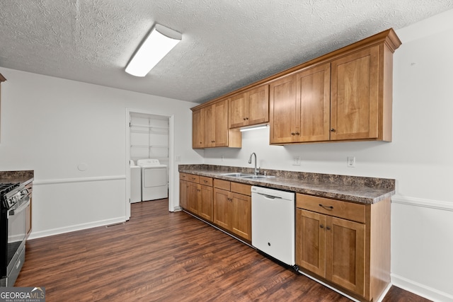 kitchen with sink, washing machine and dryer, dark hardwood / wood-style flooring, white dishwasher, and a textured ceiling