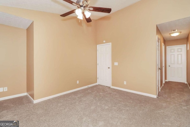 empty room featuring a textured ceiling, ceiling fan, and light carpet