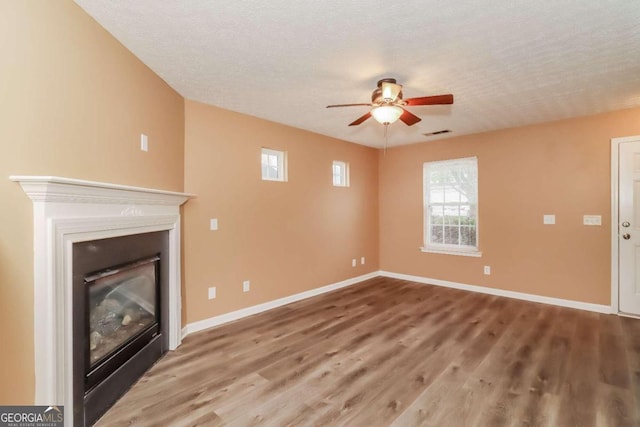 unfurnished living room with hardwood / wood-style flooring, ceiling fan, and a textured ceiling