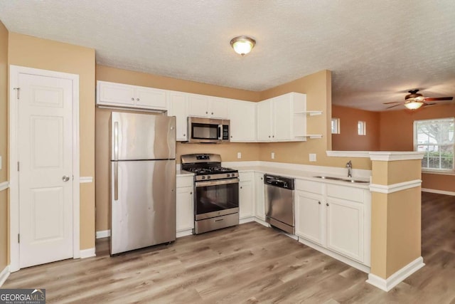 kitchen featuring white cabinets, sink, light wood-type flooring, kitchen peninsula, and stainless steel appliances