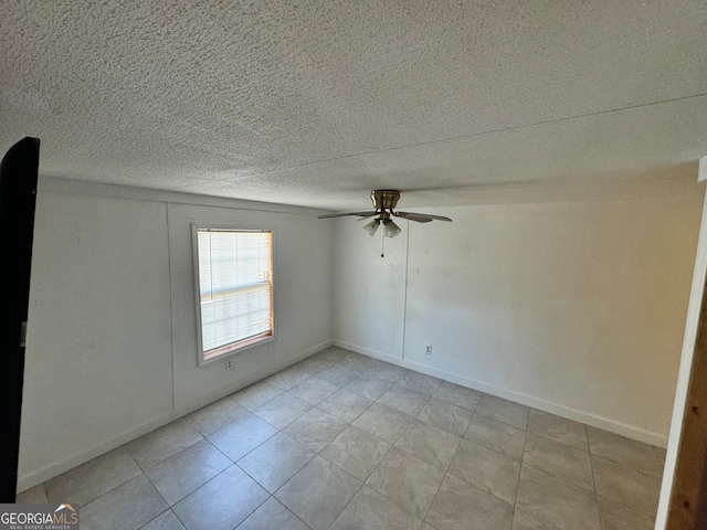 spare room featuring ceiling fan, light tile patterned floors, and a textured ceiling