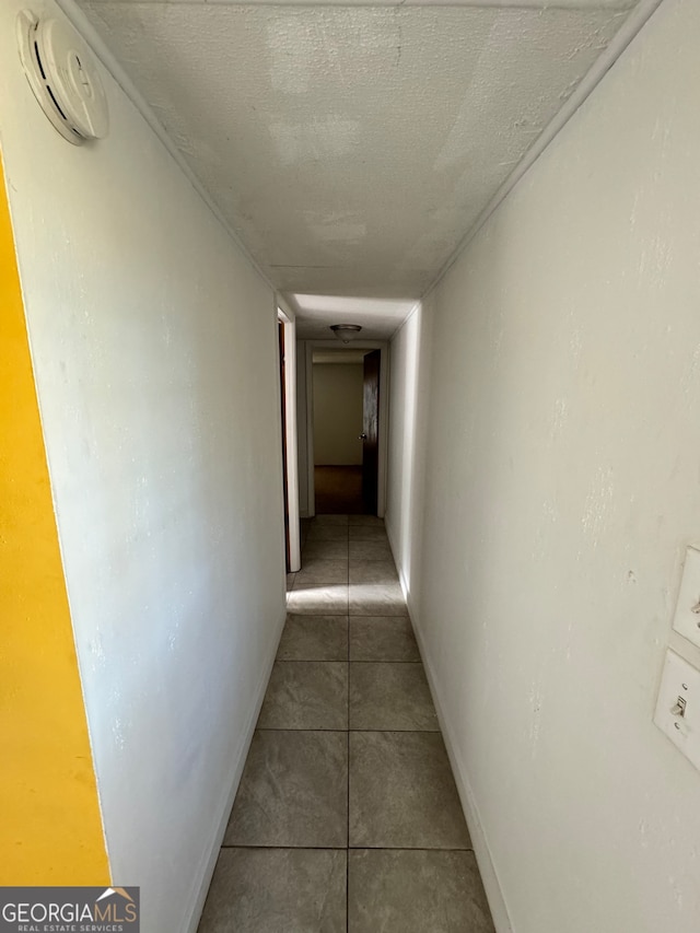 hallway with tile patterned flooring and a textured ceiling