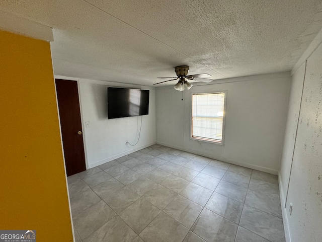 unfurnished room with ceiling fan, light tile patterned floors, and a textured ceiling