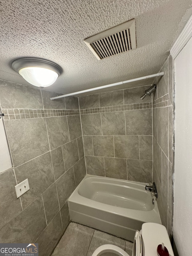 bathroom featuring tile patterned flooring, tiled shower / bath combo, and toilet